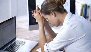 Woman sitting at desk with head in her hands