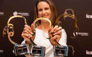 Woman holding three gold mansfield trophies won by Vero