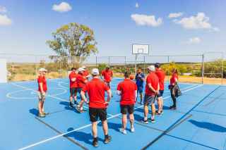 Restored basketball court after cyclone damage, with students playing in the background.