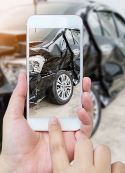 Person taking a photo of a car accident with mobile phone