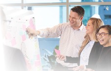 Team collaborating around whiteboard with sticky notes in modern office.