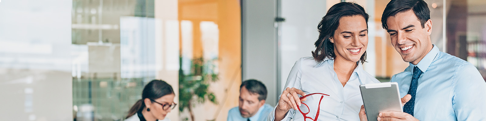 Corporate attired man and woman smiling at ipad