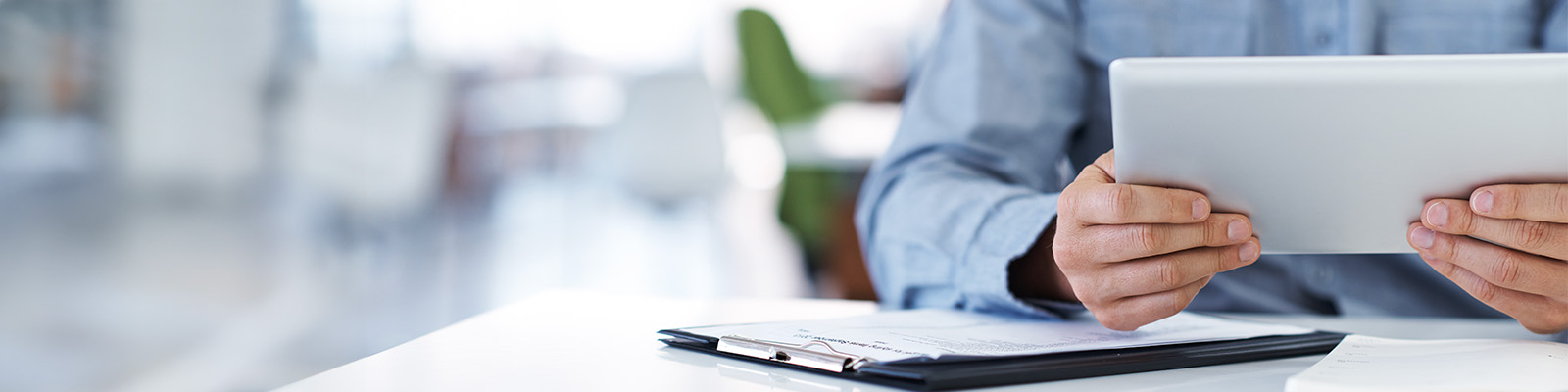 Man at desk holding laptop with pad