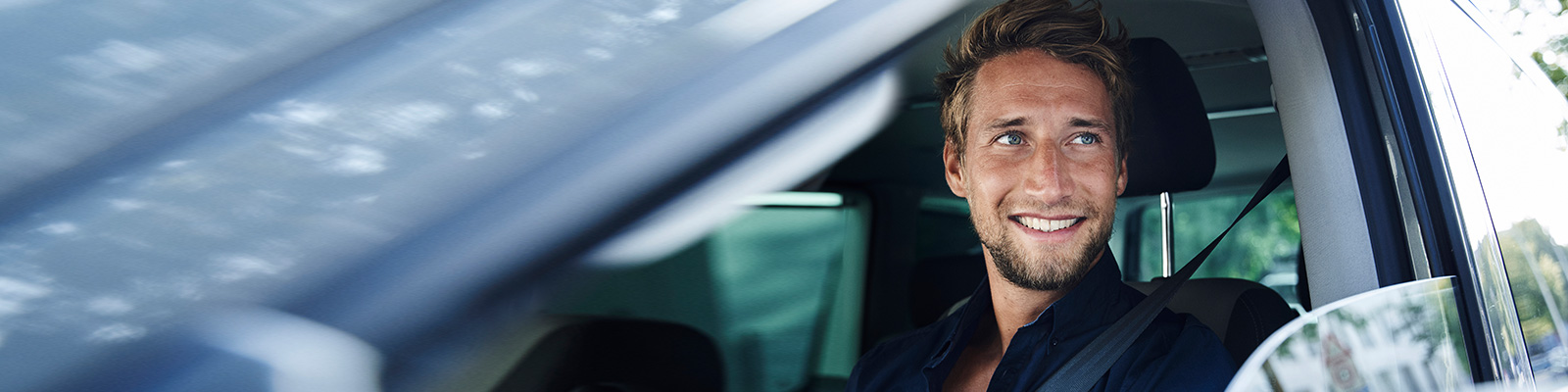 Man in a blue shirt looking out front car window