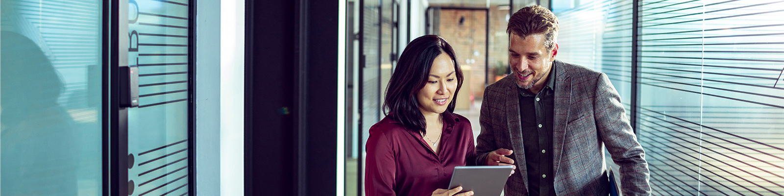 Man and woman looking at an ipad in office hallway