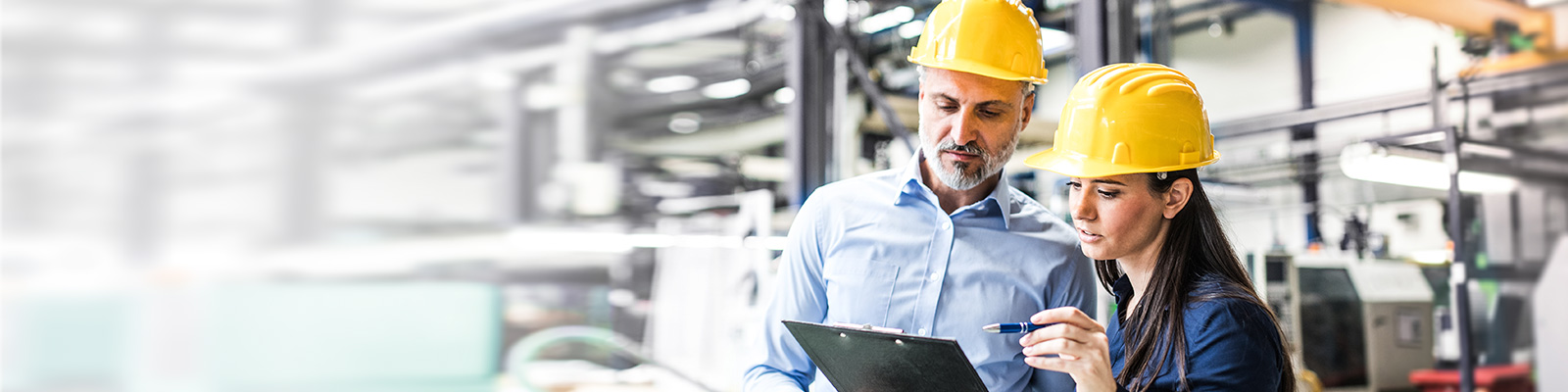 Man and woman in factory wearing yellow hard hats