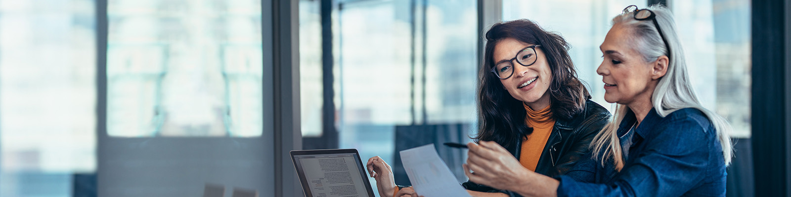 Two women working together smiling at paperwork